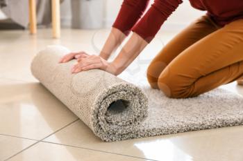 Woman rolling carpet at home�