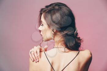 Young woman with beautiful jewelry on color background�