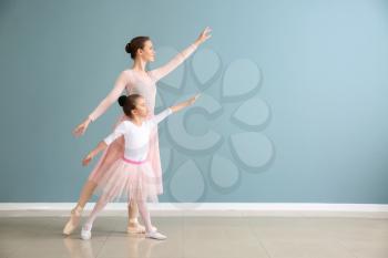 Little ballerina with coach against color wall�