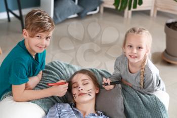 Little children drawing on face of their sleeping mother. April fools' day prank�