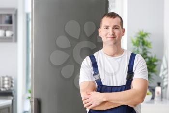 Male technician near big refrigerator in kitchen�