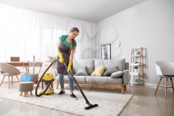 Female janitor with vacuum cleaner in room�