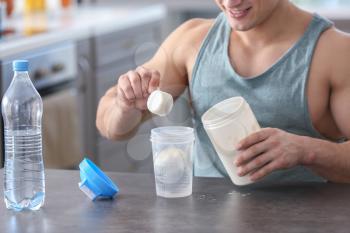 Sporty man making protein shake at home�