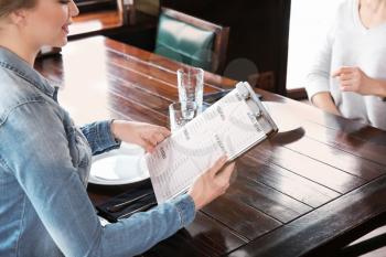 Young woman reading menu in restaurant�