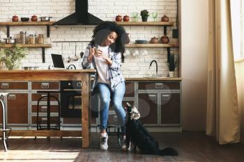 African-American woman with cute funny dog in kitchen�