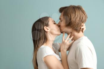Kissing young couple on color background�