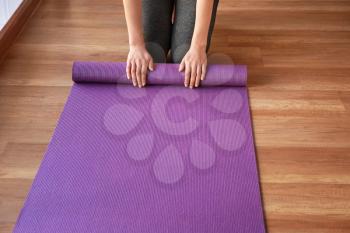 Young sporty woman with yoga mat in gym�