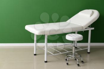 Treatment couch with stool near color wall�