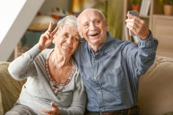 Portrait of senior couple taking selfie at home�