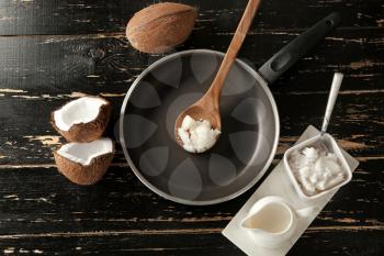 Frying pan with coconut oil on dark wooden table�