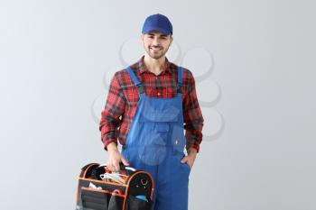Male electrician with tools kit on light background�