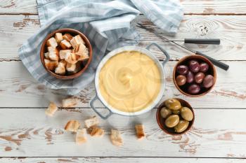 Cheese fondue with snacks on table�