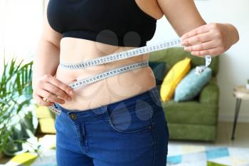 Overweight woman with measuring tape at home. Weight loss concept�