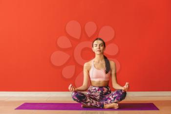 Sporty woman practicing yoga near color wall�