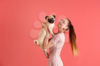 Teenage girl with cute pug dog on color background�