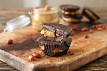 Tasty chocolate peanut butter cups on wooden board�