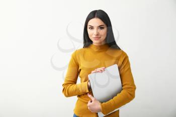 Female programmer with laptop on light background�