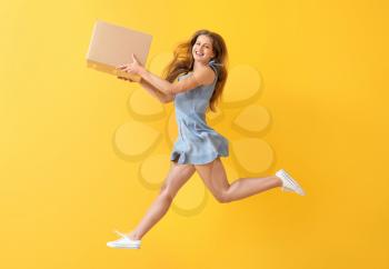 Jumping woman with cardboard box on color background�