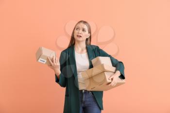Young woman with cardboard boxes on color background�