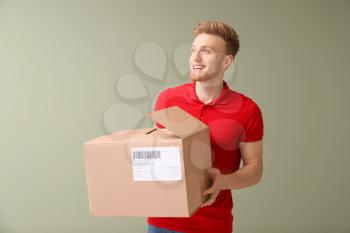 Young man with cardboard box on color background�