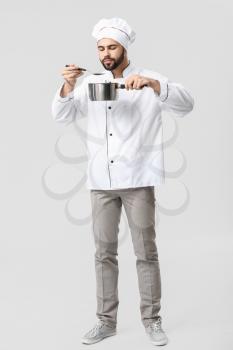 Handsome male chef with pot on white background�