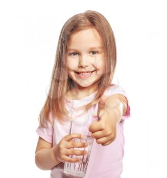 Cute little girl with glass of water showing thumb-up gesture on white background�