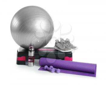 Set of sports equipment with fitness ball, shoes and bottle of water on white background�