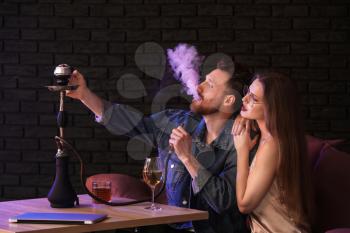 Young couple smoking hookah in cafe�