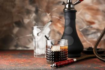 Glass of cold whiskey with hookah on table�