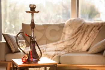 Hookah, pomegranate and glass of alcohol on table in room�