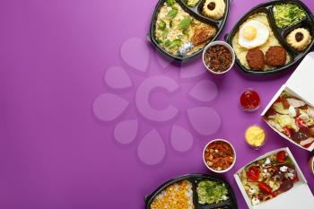 Containers with delicious food on color background�
