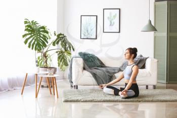 Young woman practicing yoga at home�