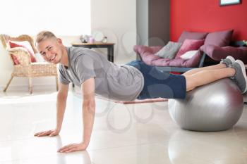 Young man doing exercise with fitball at home�