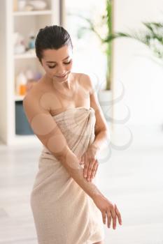 Beautiful young woman applying body scrub at home�