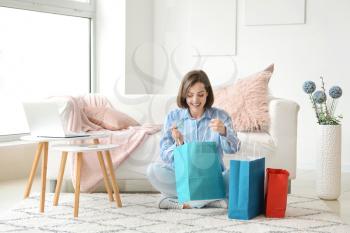 Young woman with shopping bags sitting at home�
