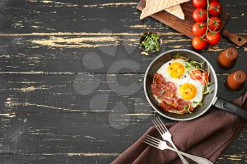 Composition with tasty fried eggs and bacon on wooden table�
