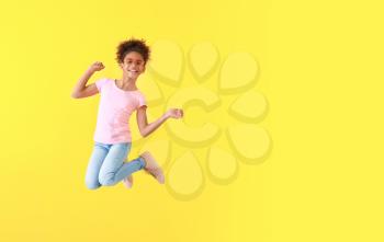Jumping African-American girl in jeans on color background�