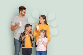 Young family with glasses of tasty milk on light background�