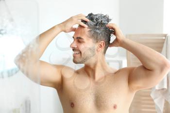 Handsome man washing hair in bathroom�