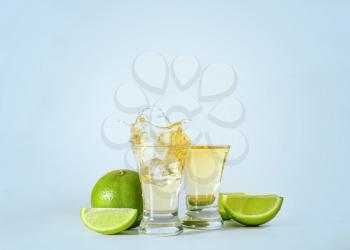 Shots of tequila with splashes on light background�