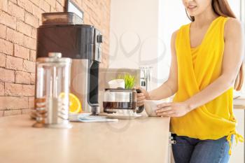 Beautiful woman using coffee machine in kitchen�
