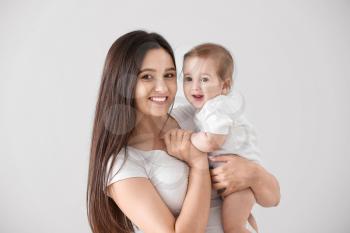 Happy mother with cute little baby on light background�