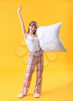 Young woman with pillow and sleep mask on color background�