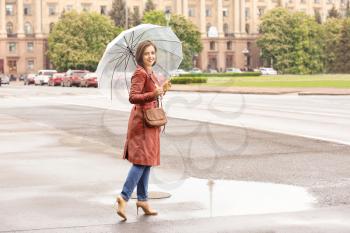 Beautiful young woman with umbrella outdoors on rainy day�