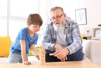 Cute little boy playing with grandfather at home�