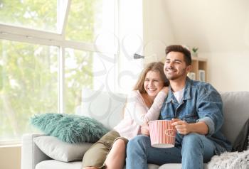 Happy couple watching TV at home�