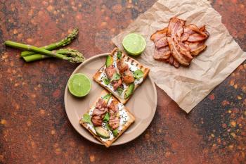 Plate with tasty toasts and bacon on color background�