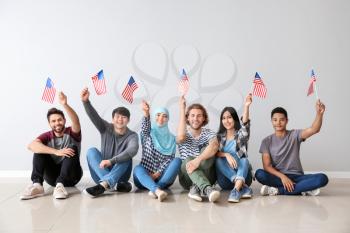 Group of students with USA flags sitting near light wall�