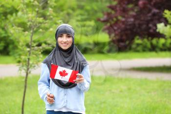 Female Muslim student with Canadian flag outdoors�