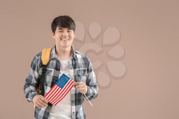 Young Asian student with USA flag on color background�